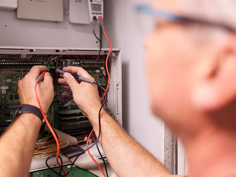Informationselektroniker vor einem Schaltschrank überprüft Verbindungen für maximale Sicherheit